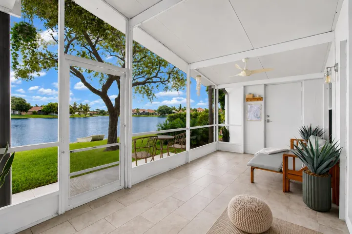 Screened patio featuring light-toned tile flooring, a ceiling fan, and sliding glass door access