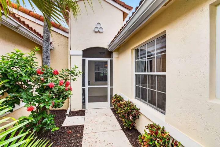 Entryway featuring a screened front door, a decorative arched alcove, and stucco exterior walls