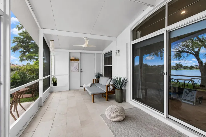 Screened-in porch featuring a ceiling fan, light-toned tile flooring, and direct access to the interior via sliding glass doors
