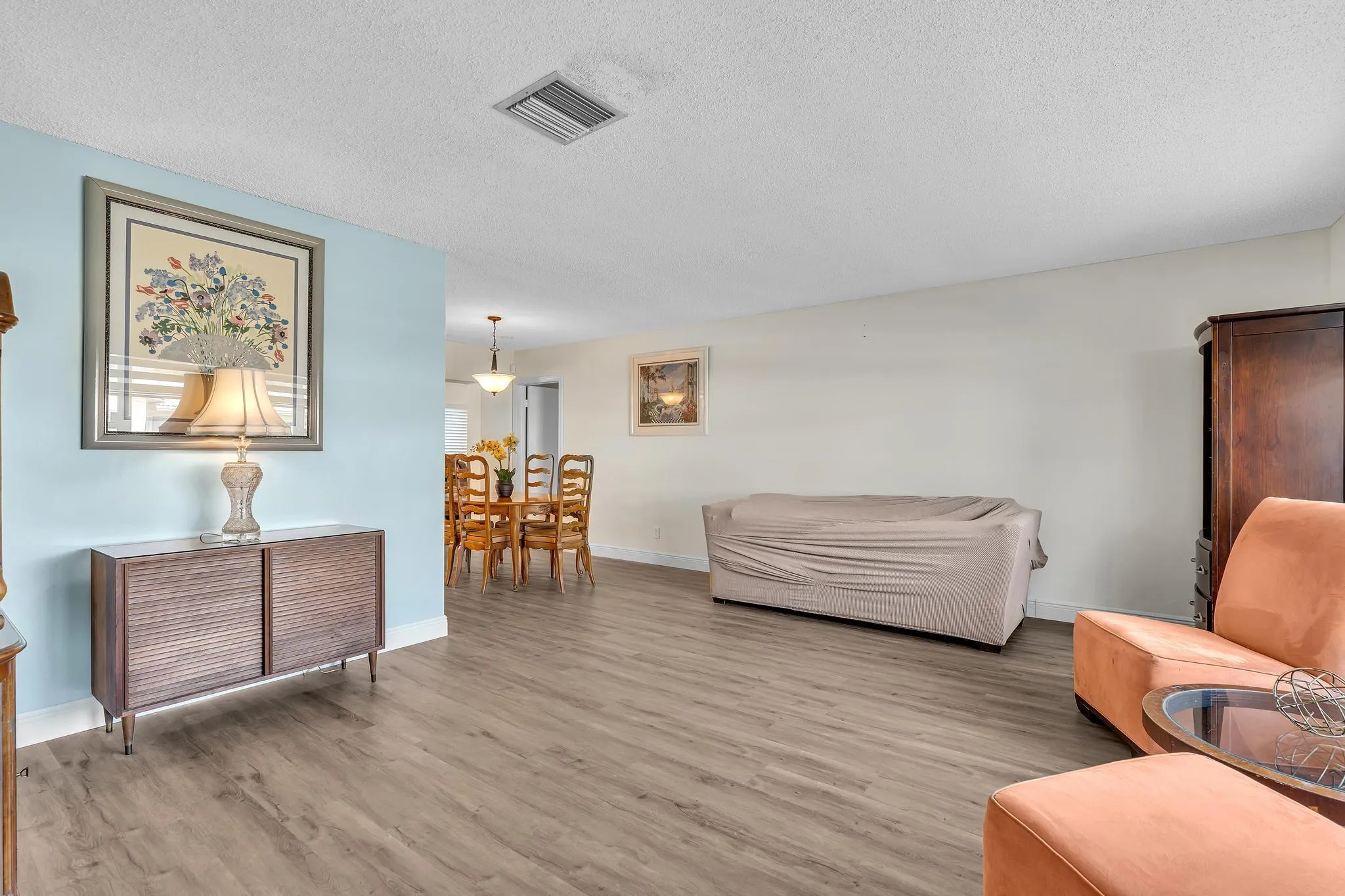 Expansive living area with wood-finish flooring, a light blue accent wall, and recessed lighting