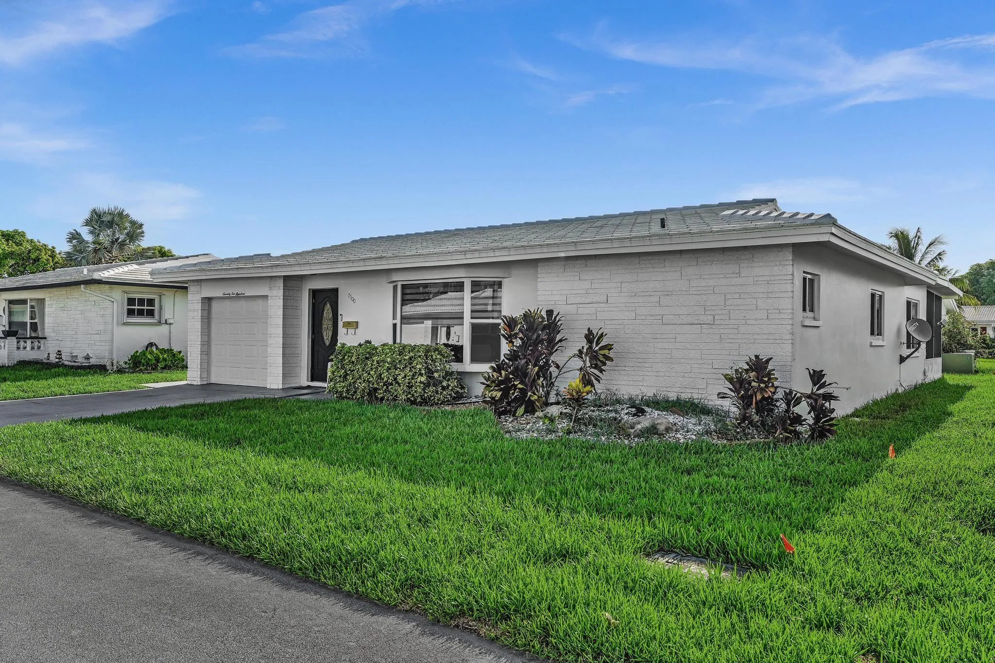 Single-story residence featuring a textured facade, a covered entry, and an attached garage