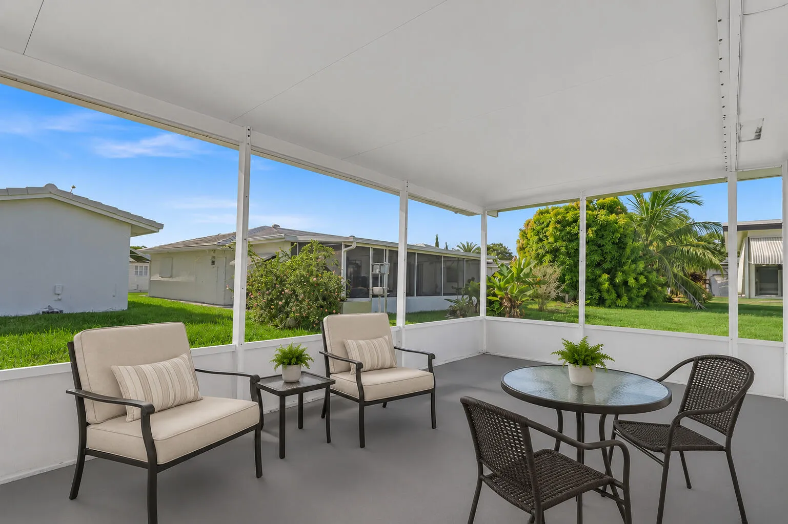 Screened patio featuring a solid roof, concrete flooring, and surrounding landscaping