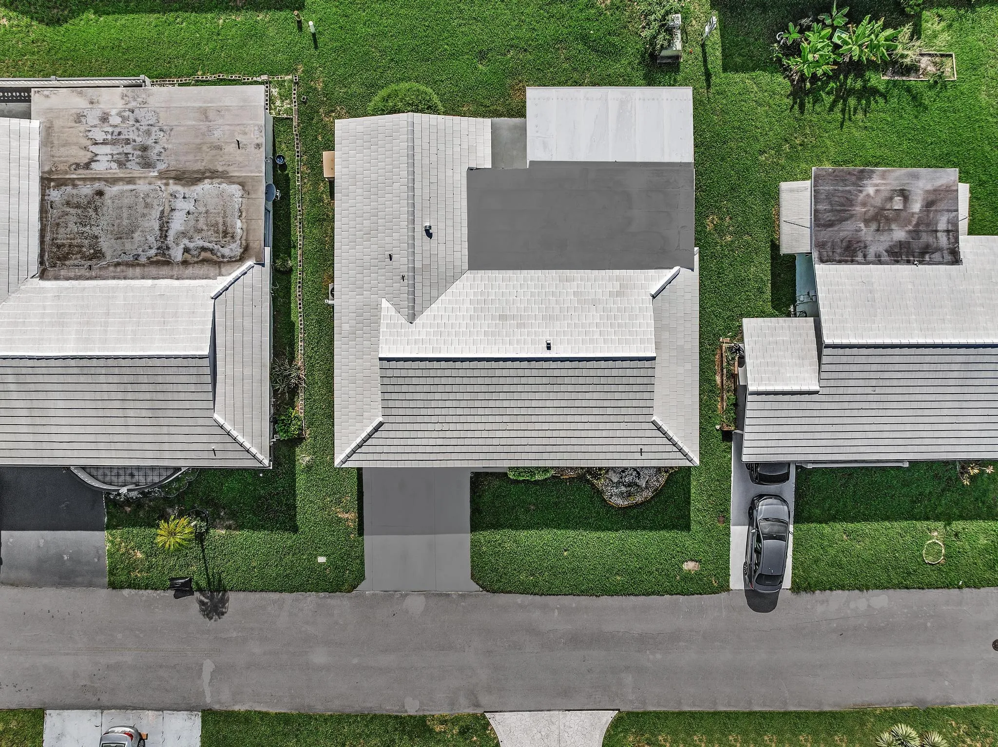 Overhead property view featuring a light-colored shingled roof, an attached carport, and a concrete driveway