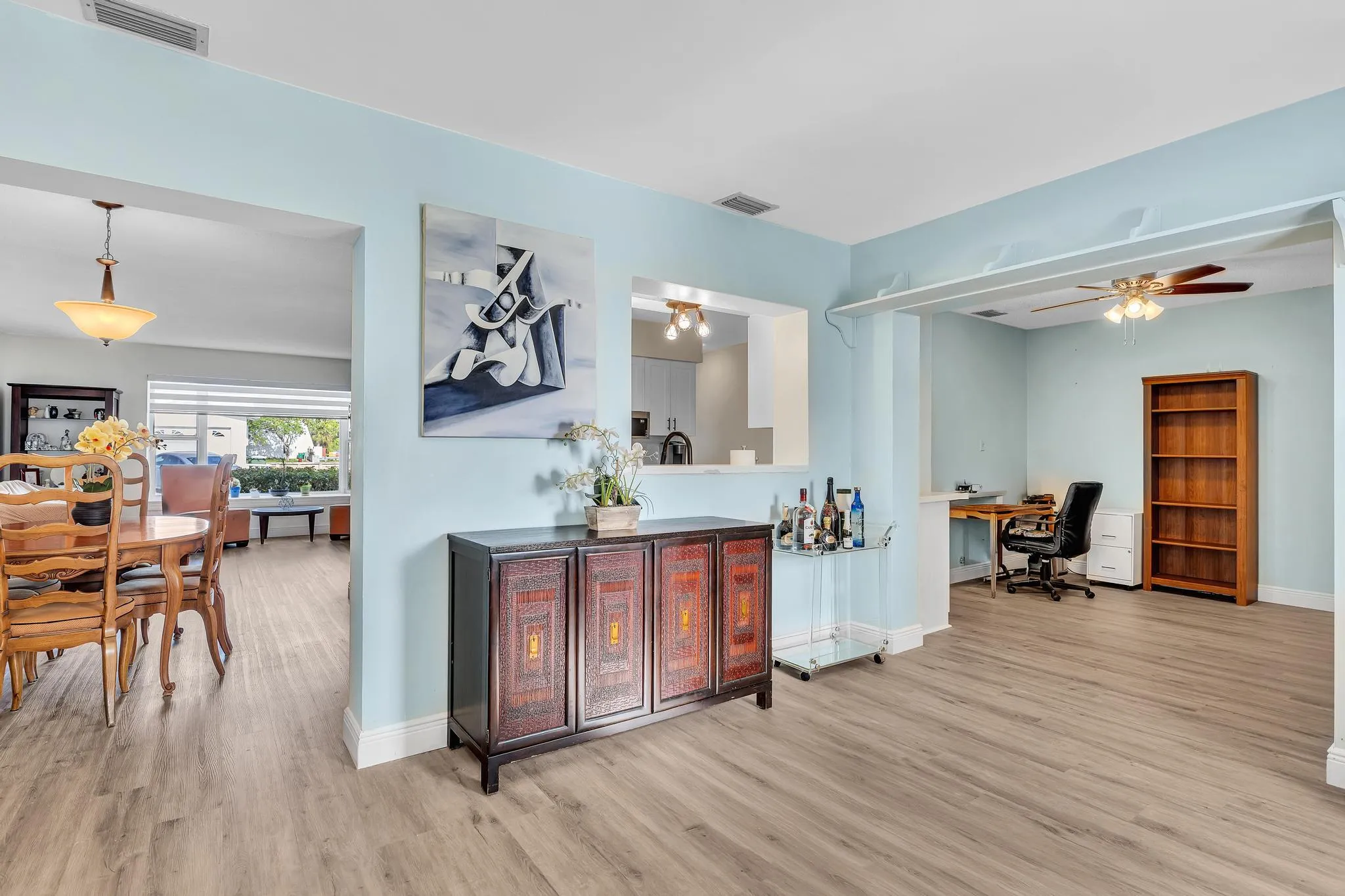 Open-concept interior featuring wood-finish flooring, light blue wall paint, and white trim throughout
