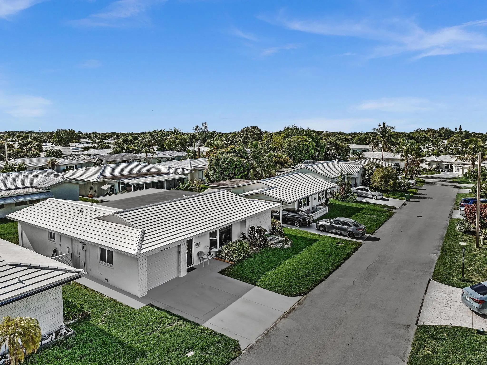Contemporary single-story residence featuring a white tile roof and a concrete driveway