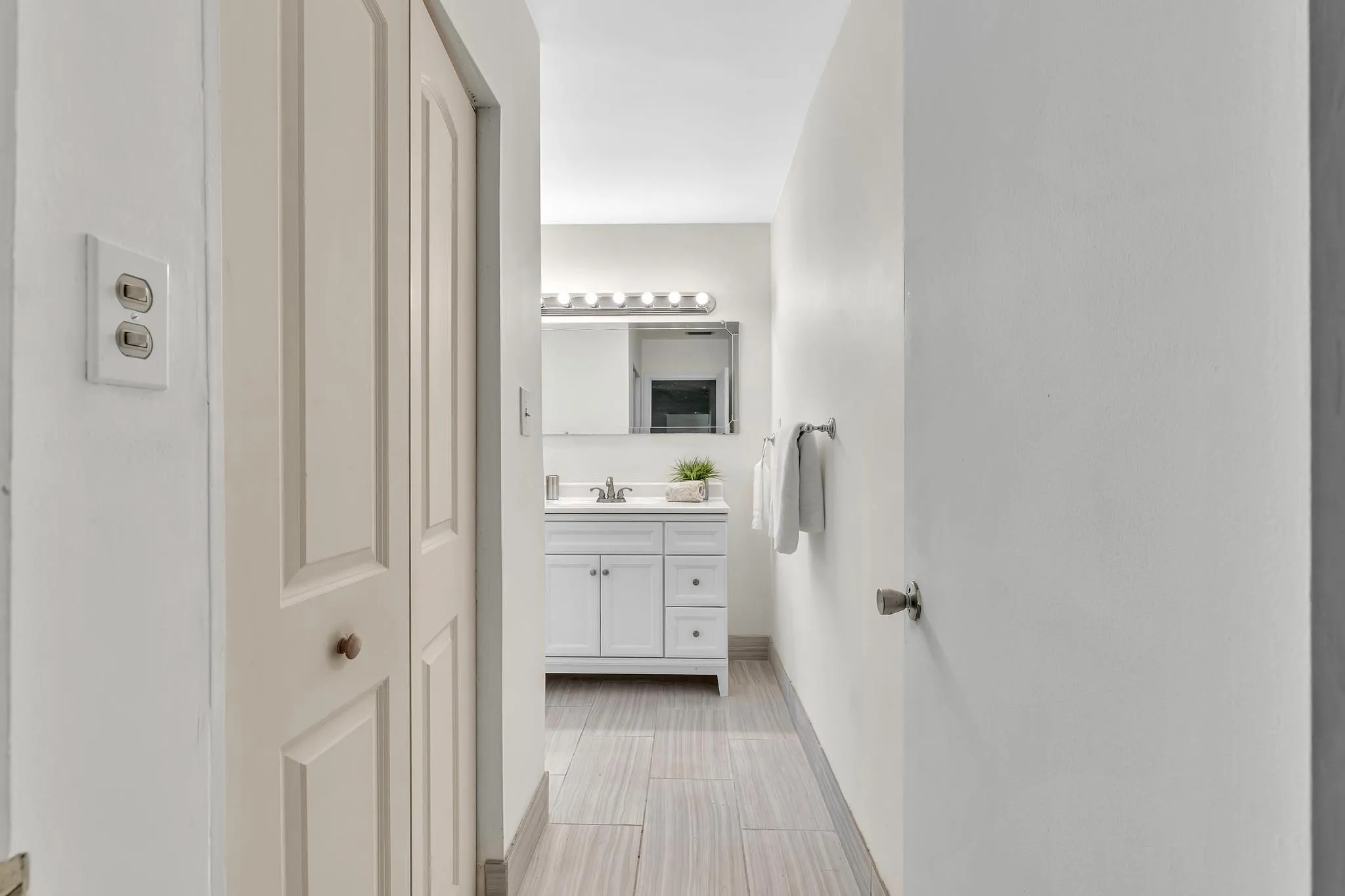 Hallway bathroom featuring a vanity with white cabinetry, a single basin sink, and a mirrored medicine cabinet