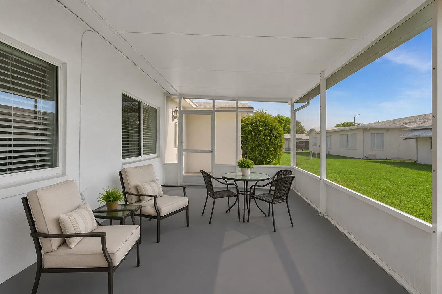 Screened patio with a painted concrete floor, white exterior walls, and multiple windows with blinds