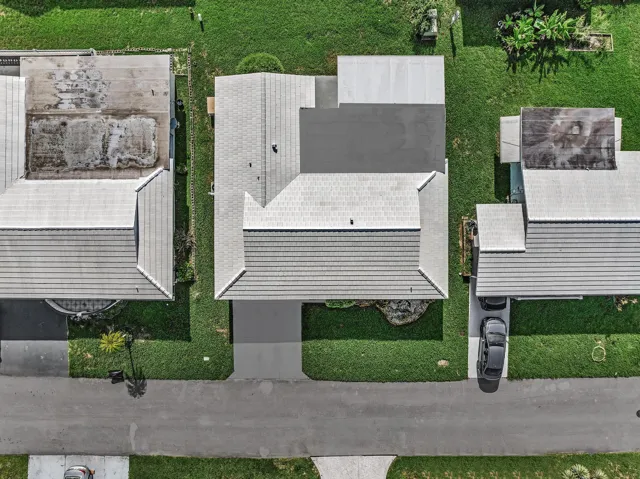 Overhead property view featuring a light-colored shingled roof, an attached carport, and a concrete driveway