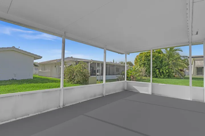Screened patio featuring a solid roof, concrete flooring, and surrounding landscaping