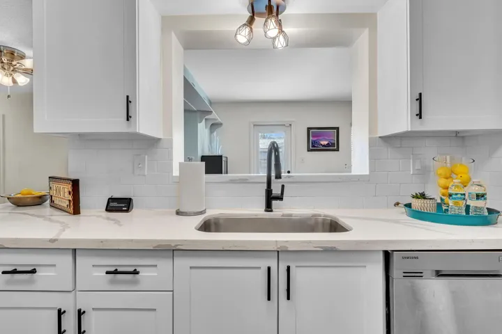 Kitchen featuring white shaker-style cabinetry with matte black hardware, white subway tile backsplash, and light-colored countertops