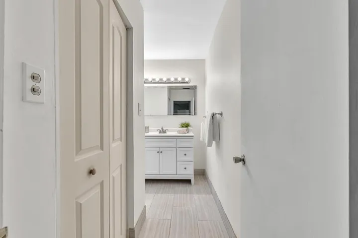 Hallway bathroom featuring a vanity with white cabinetry, a single basin sink, and a mirrored medicine cabinet