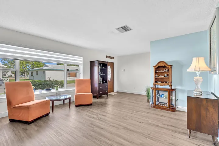 Spacious room featuring wood-finish flooring, a large picture window with horizontal blinds, and light-toned walls