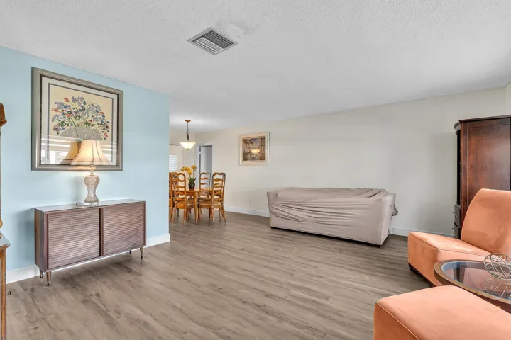Expansive living area with wood-finish flooring, a light blue accent wall, and recessed lighting