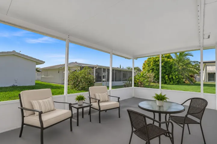 Screened patio featuring a solid roof, concrete flooring, and surrounding landscaping