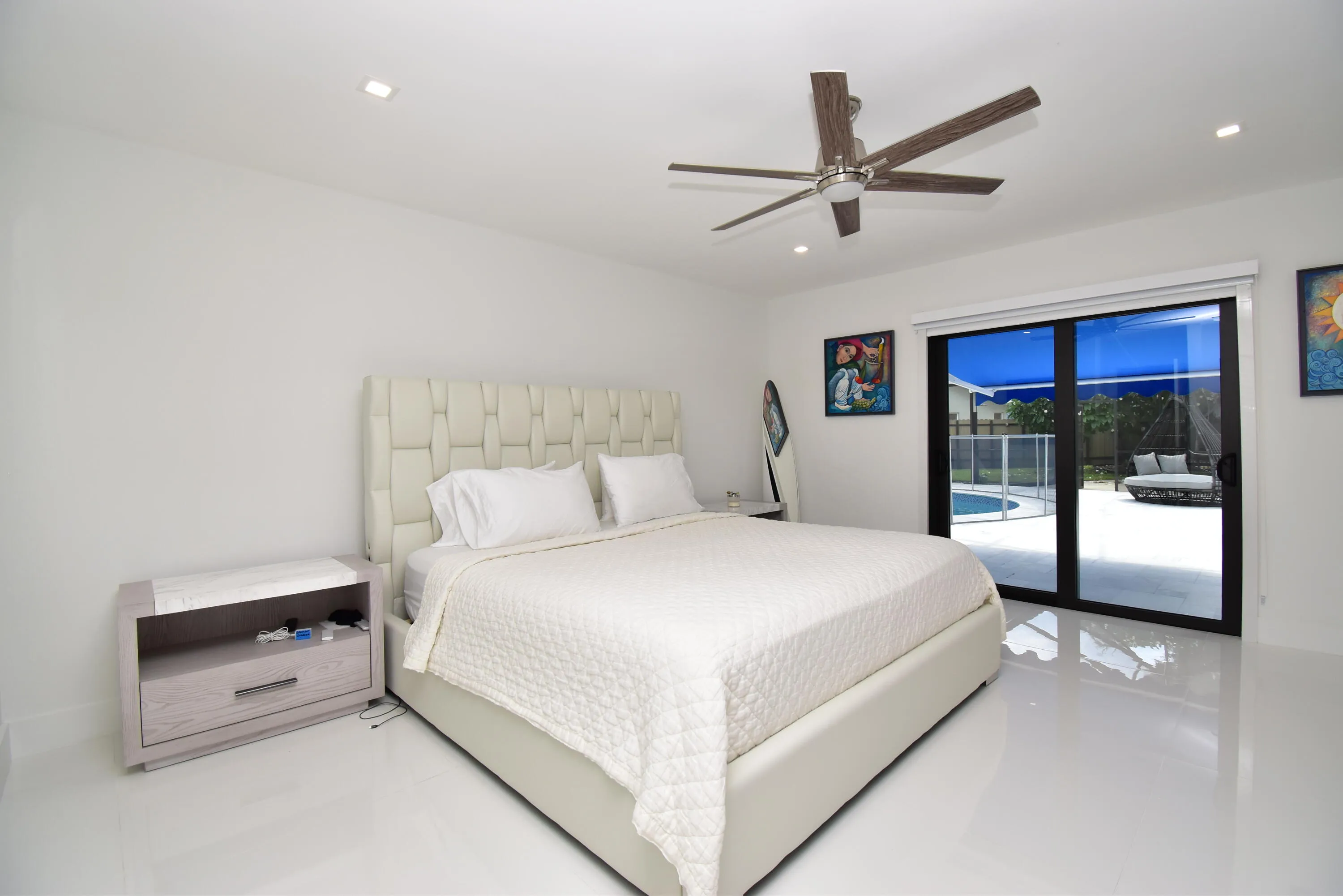 Recessed lighting illuminates this bright room featuring a ceiling fan, sliding glass doors, and a private patio with a pool