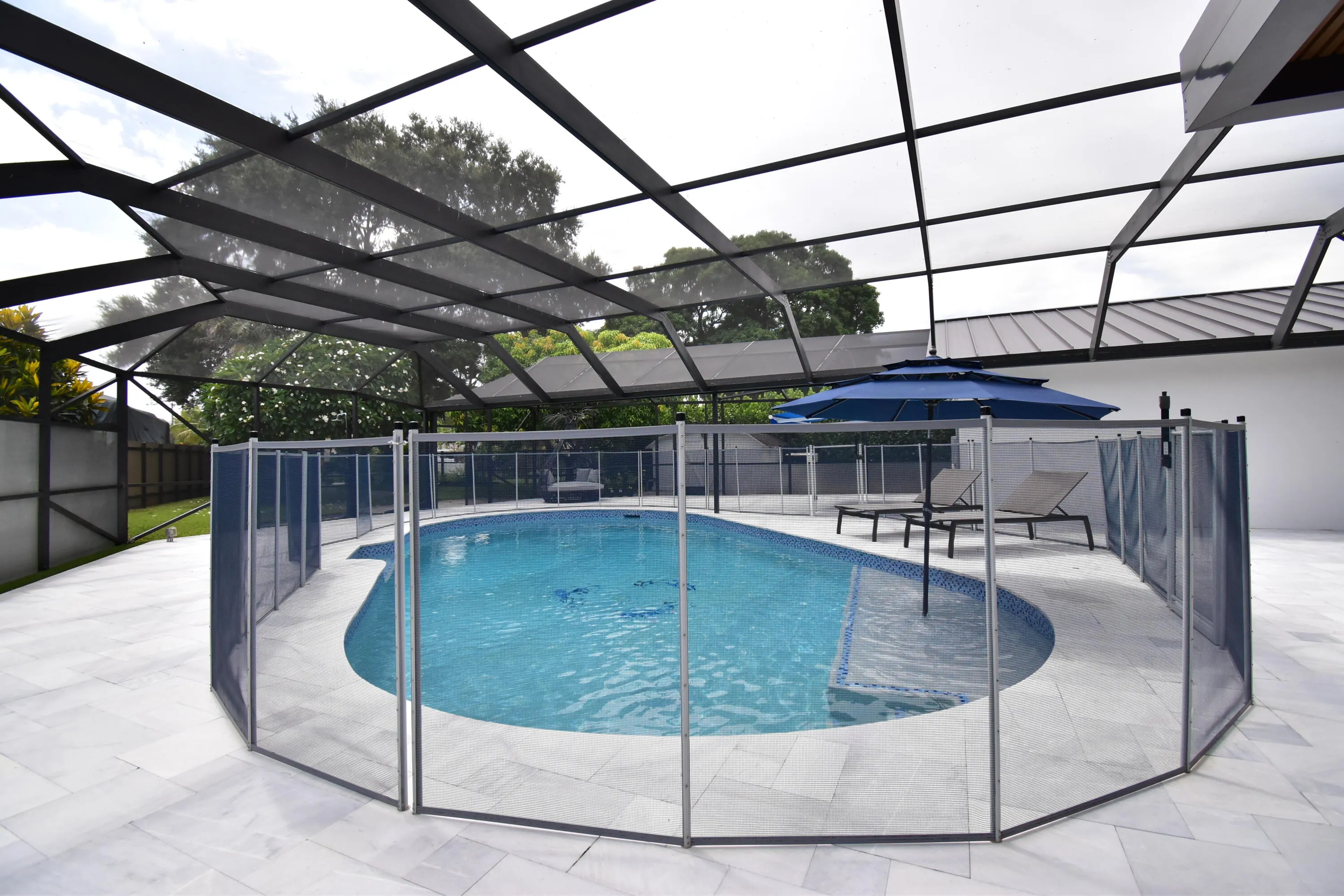 Screened-in pool area featuring a curved swimming pool, tiled pool interior, and perimeter safety fencing