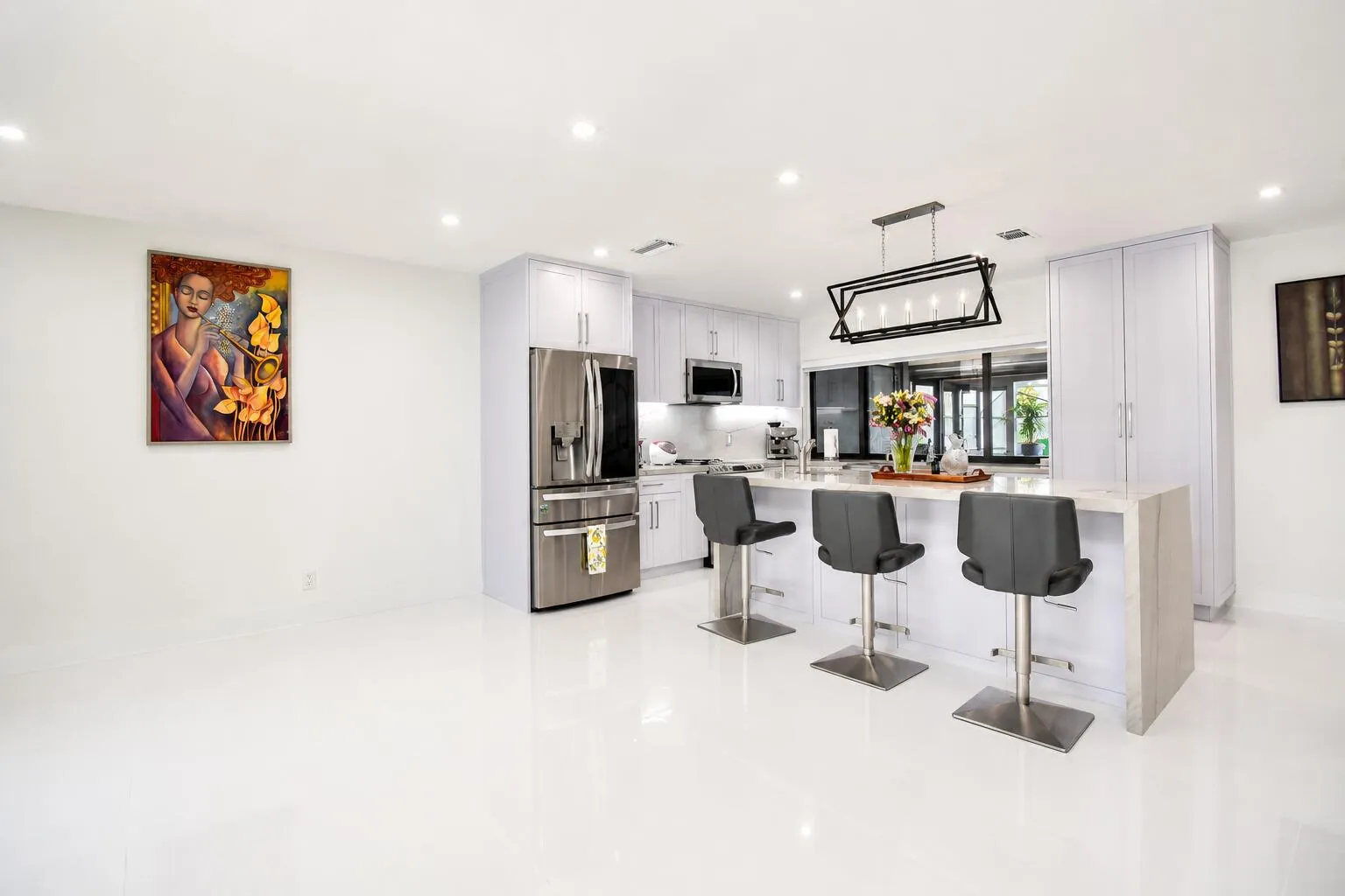 Modern kitchen featuring white cabinetry, stainless steel appliances, and a central island with countertop seating