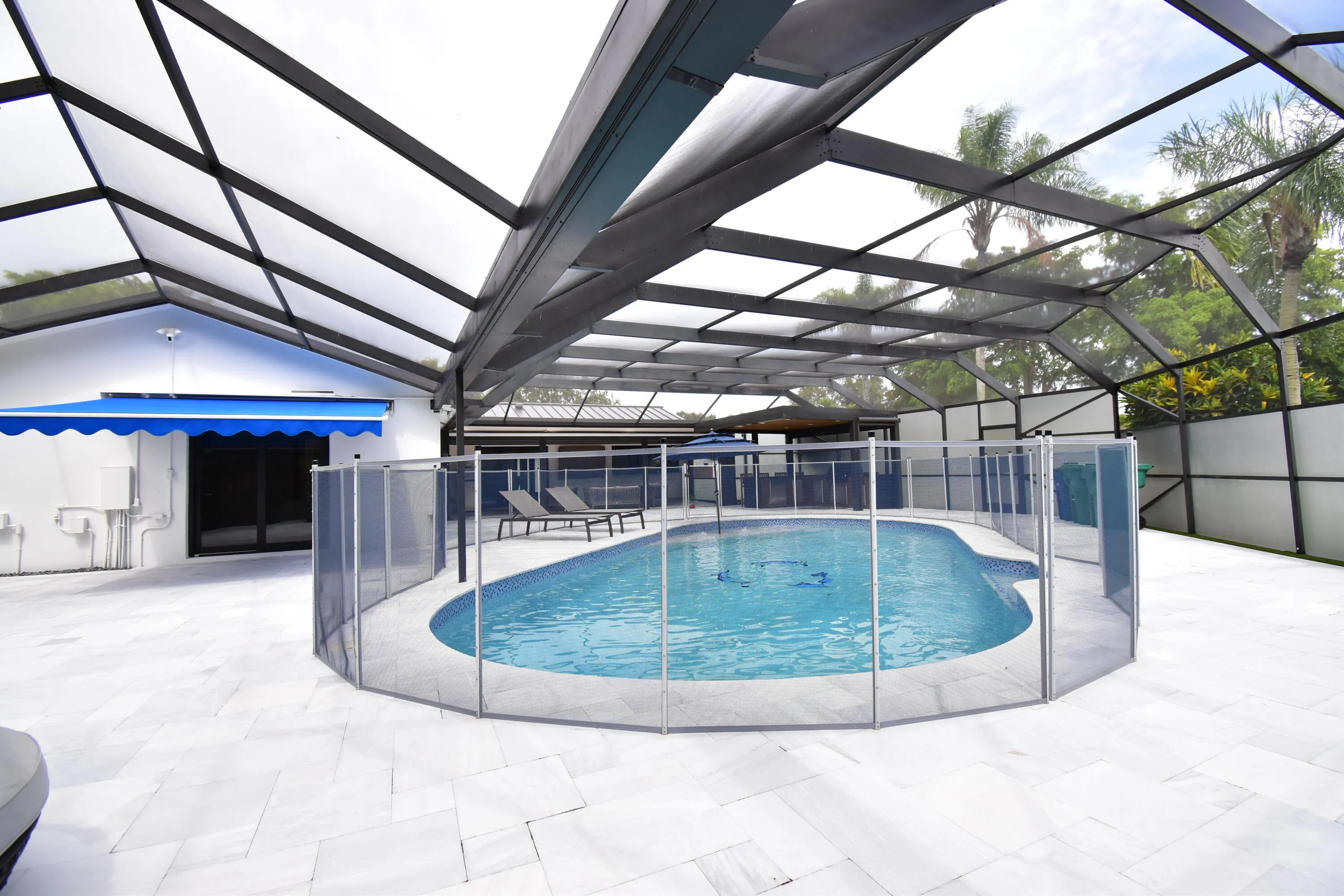 Screen-enclosed pool area featuring a freeform swimming pool with a surrounding safety fence