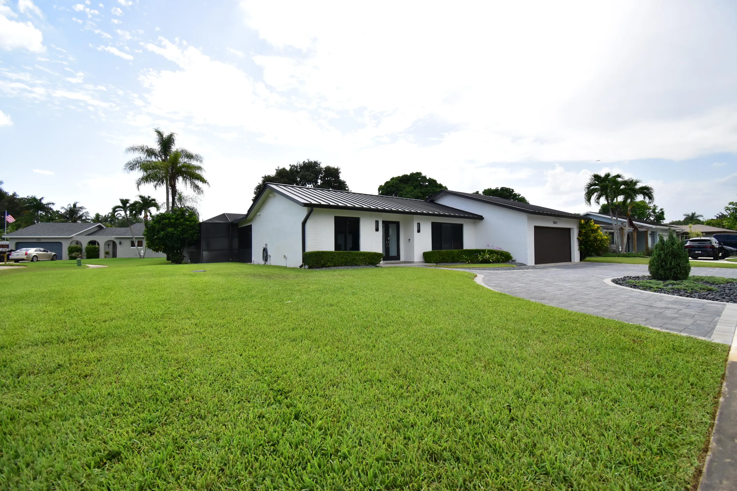 Contemporary single-story residence with a dark metal roof and white exterior