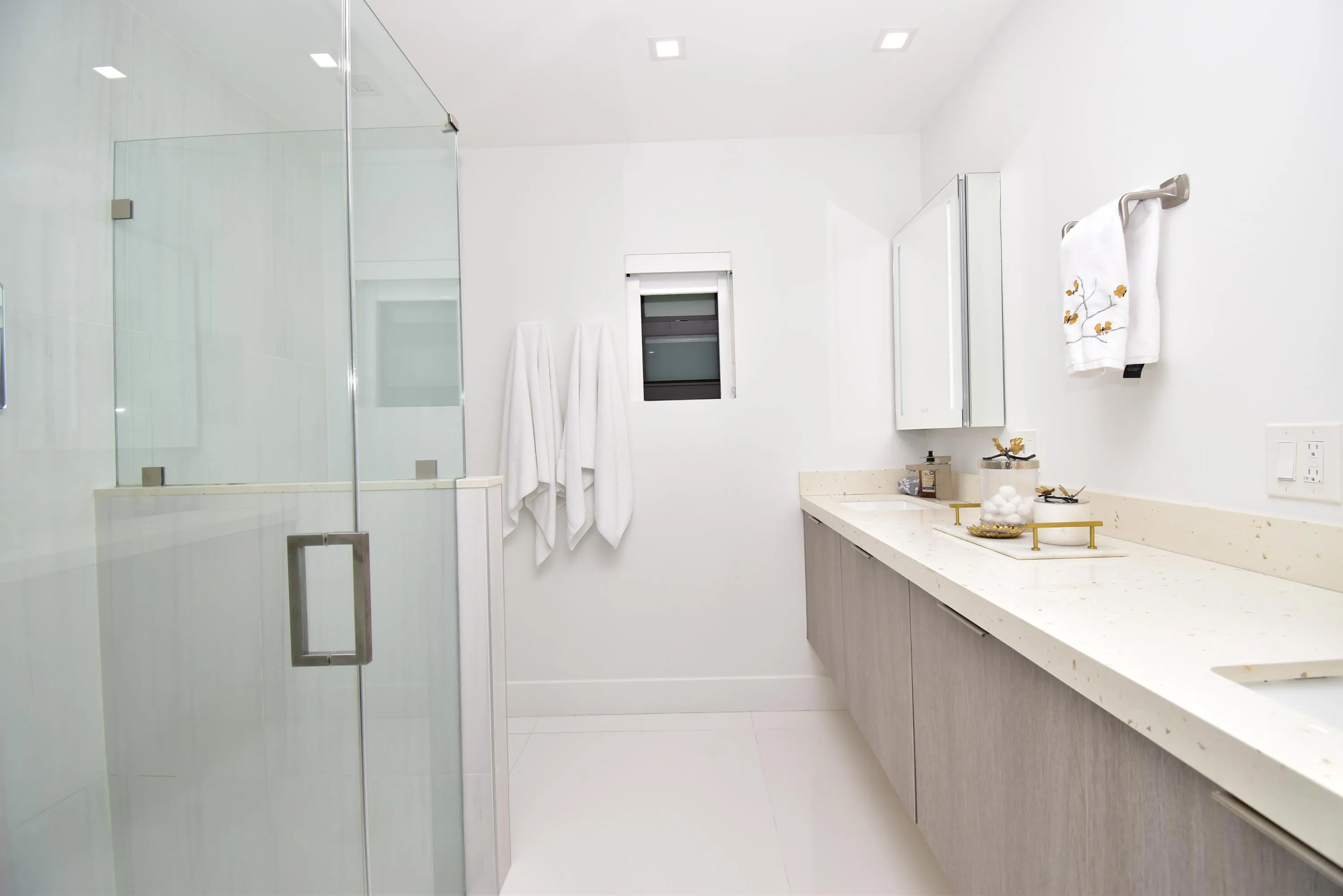 Modern bathroom featuring a frameless glass shower enclosure, a floating vanity with wood-finish cabinetry, a light-toned countertop, and recessed ceiling lighting