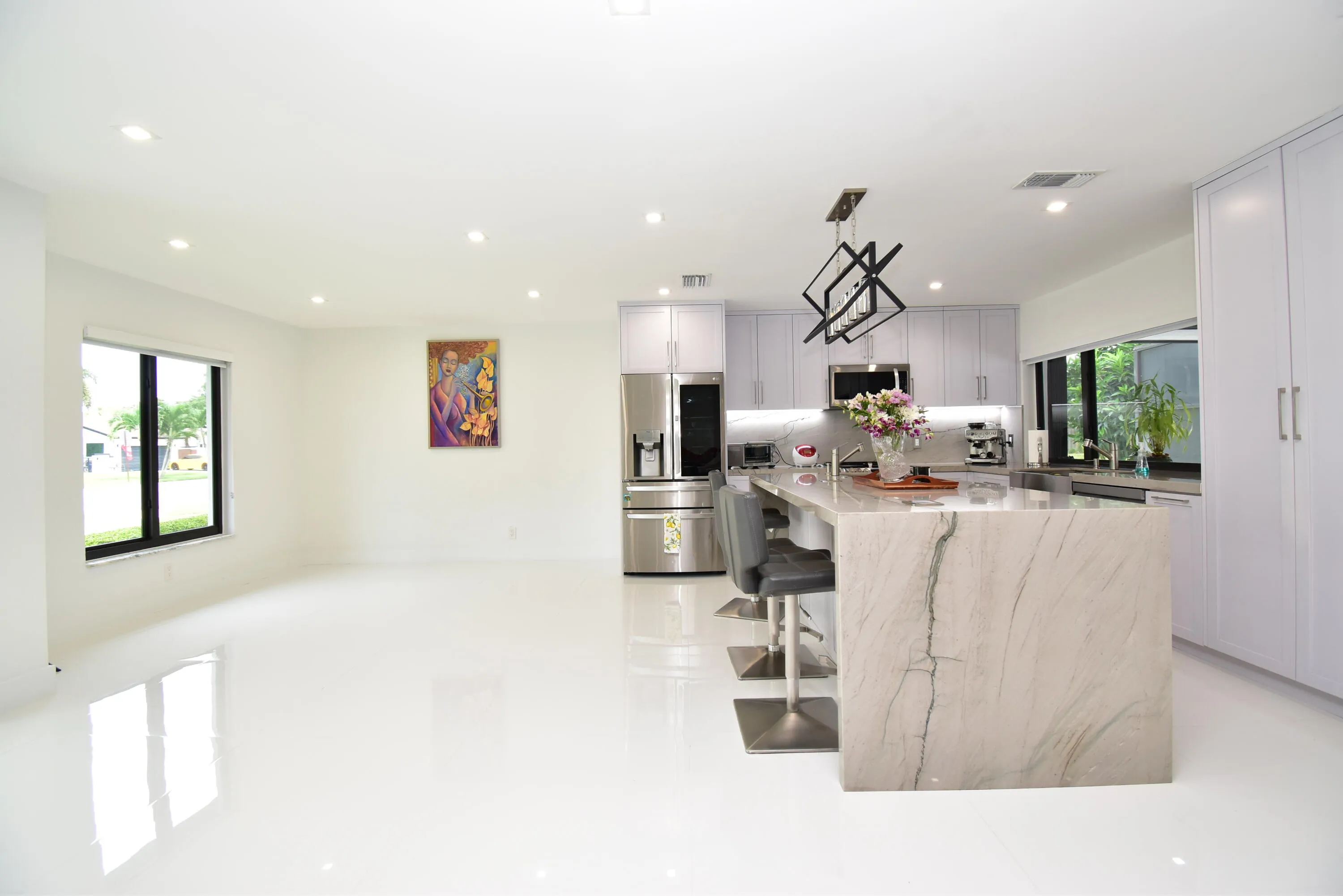 Open-concept living space featuring a gourmet kitchen with a waterfall island, stainless steel appliances, recessed lighting, and expansive windows