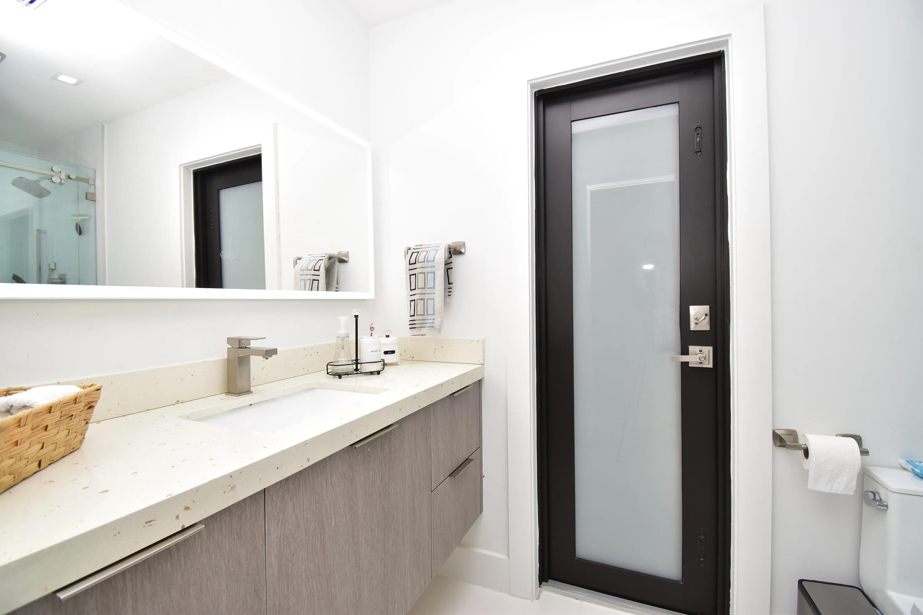 Bathroom vanity featuring a light-colored countertop with an undermount sink, brushed nickel faucet, and wood-finish cabinetry