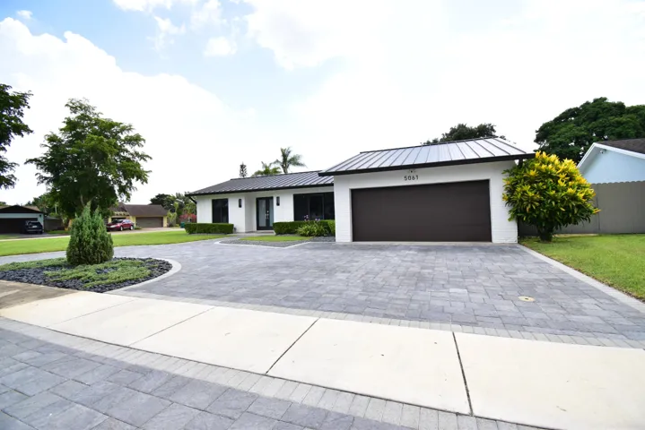 White brick facade with dark trim accents and a black metal roof
