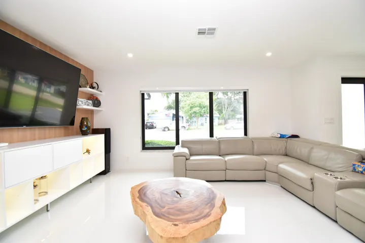 Bright living area featuring recessed lighting, a large window with black framing, and a built-in media console with open and closed storage