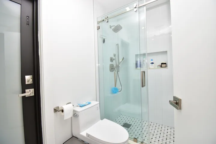 Bathroom featuring a glass-enclosed shower with sliding door, wall-mounted shower system, and recessed shelving