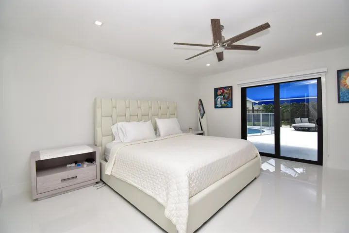 Recessed lighting illuminates this bright room featuring a ceiling fan, sliding glass doors, and a private patio with a pool