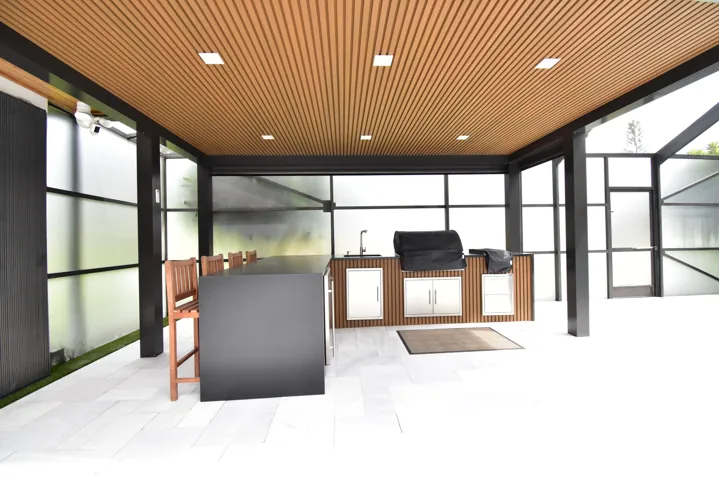 Covered outdoor kitchen featuring a wood-slat ceiling, recessed lighting, integrated sink, and stainless steel cabinetry