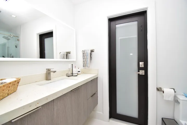 Bathroom vanity featuring a light-colored countertop with an undermount sink, brushed nickel faucet, and wood-finish cabinetry