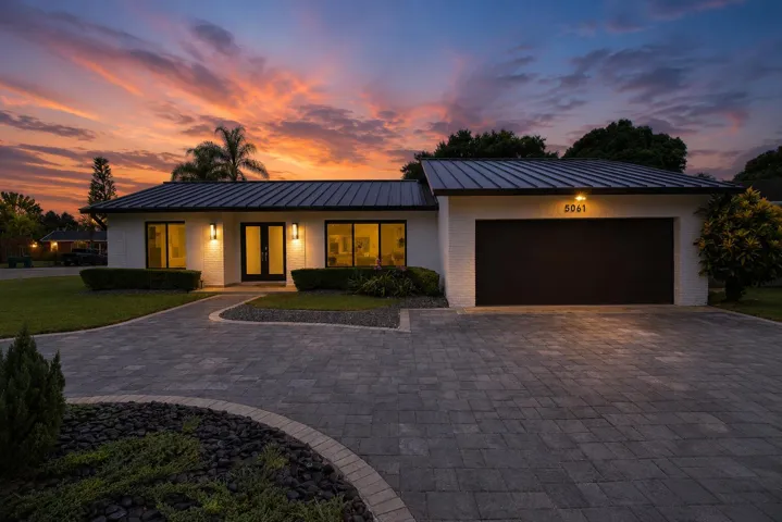 Modern single-story residence with a dark metal roof and white brick exterior