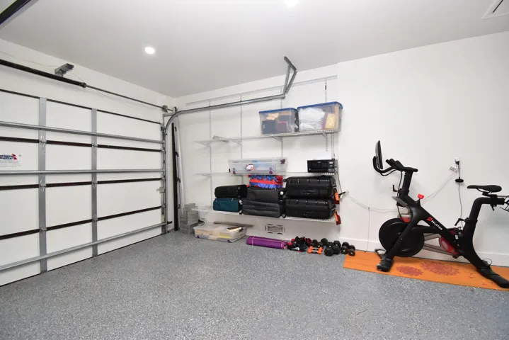 Garage space featuring a speckled epoxy floor, white walls, and a paneled garage door