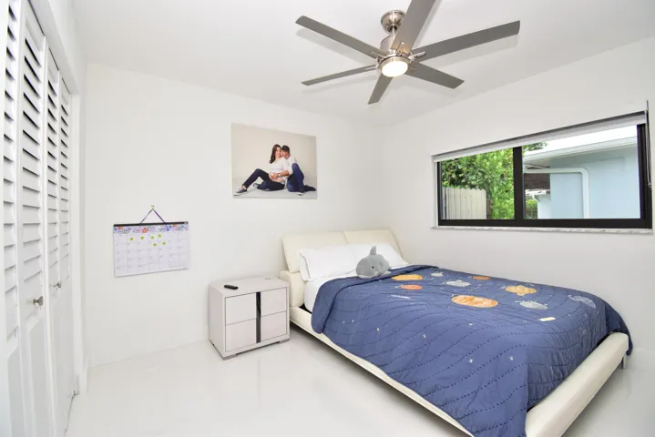 Bright interior space featuring a ceiling fan with integrated lighting, a horizontal window with exterior landscaping visible, and louvered closet doors