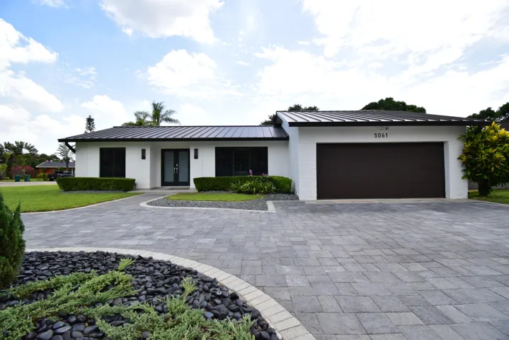 Contemporary residence featuring a crisp white facade and a dark metal roof