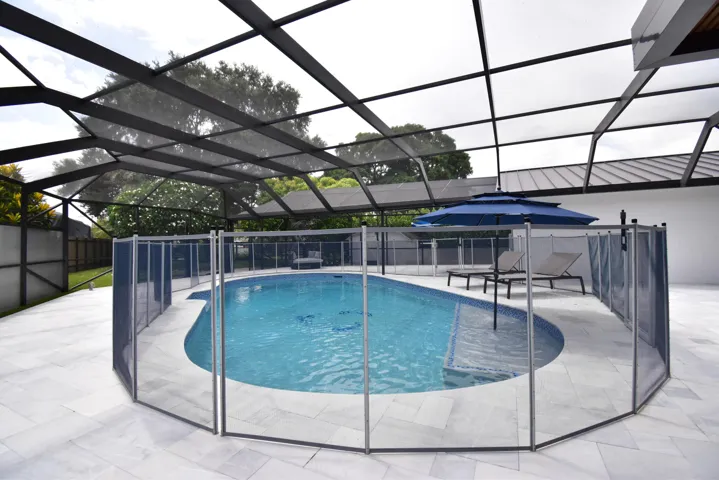 Screened-in pool area featuring a curved swimming pool, tiled pool interior, and perimeter safety fencing