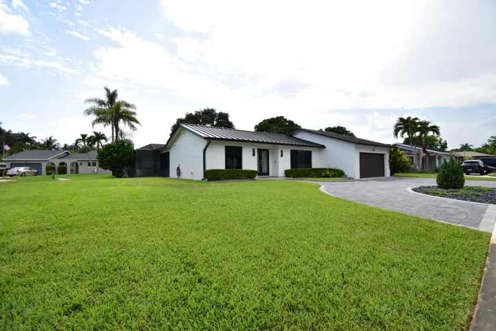 Contemporary single-story residence with a dark metal roof and white exterior