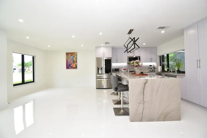 Open-concept living space featuring a gourmet kitchen with a waterfall island, stainless steel appliances, recessed lighting, and expansive windows