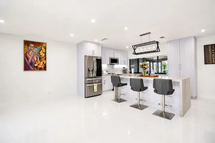 Modern kitchen featuring white cabinetry, stainless steel appliances, and a central island with countertop seating