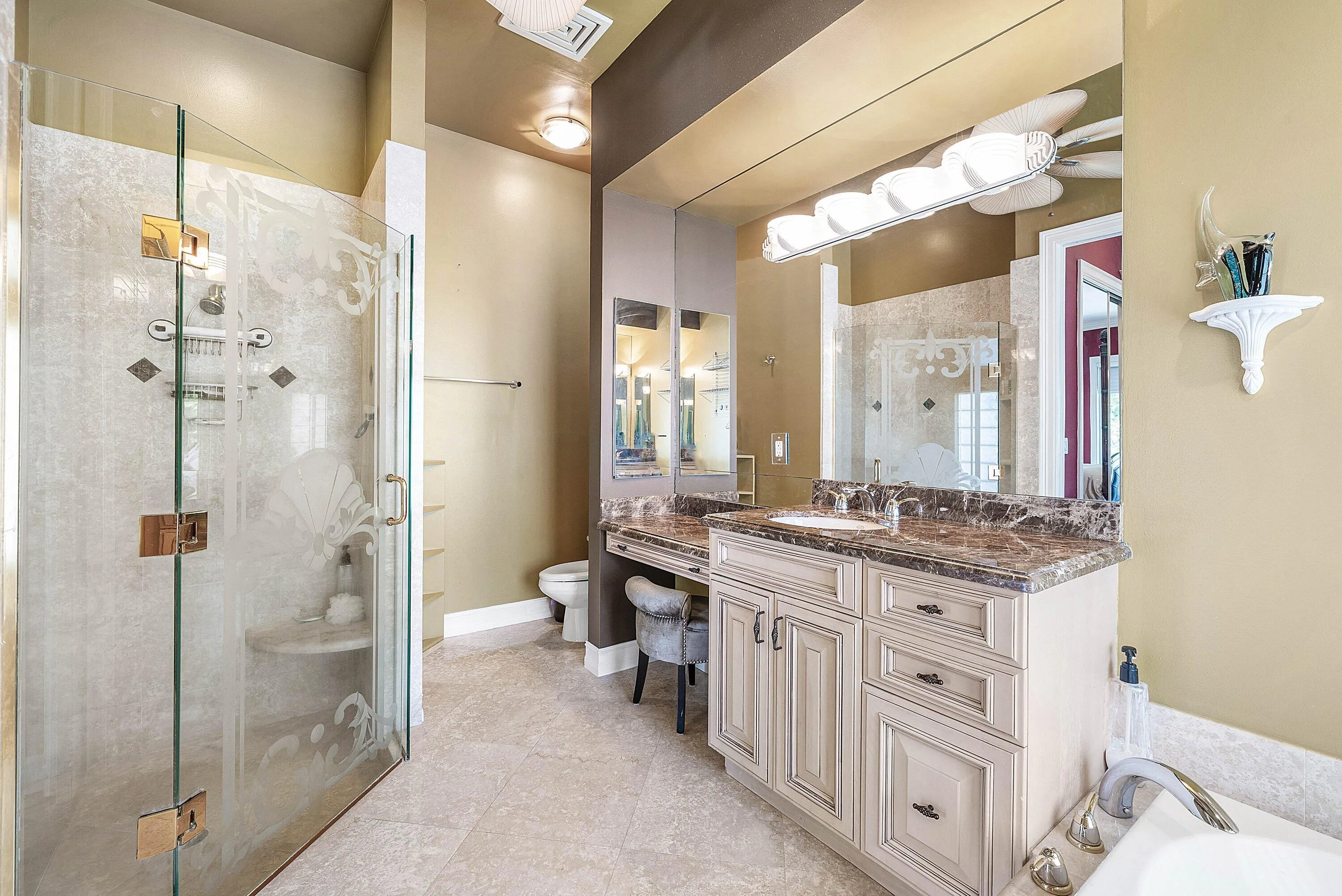 Spacious bathroom featuring a glass-enclosed shower with decorative etching, integrated bench, and tiled walls
