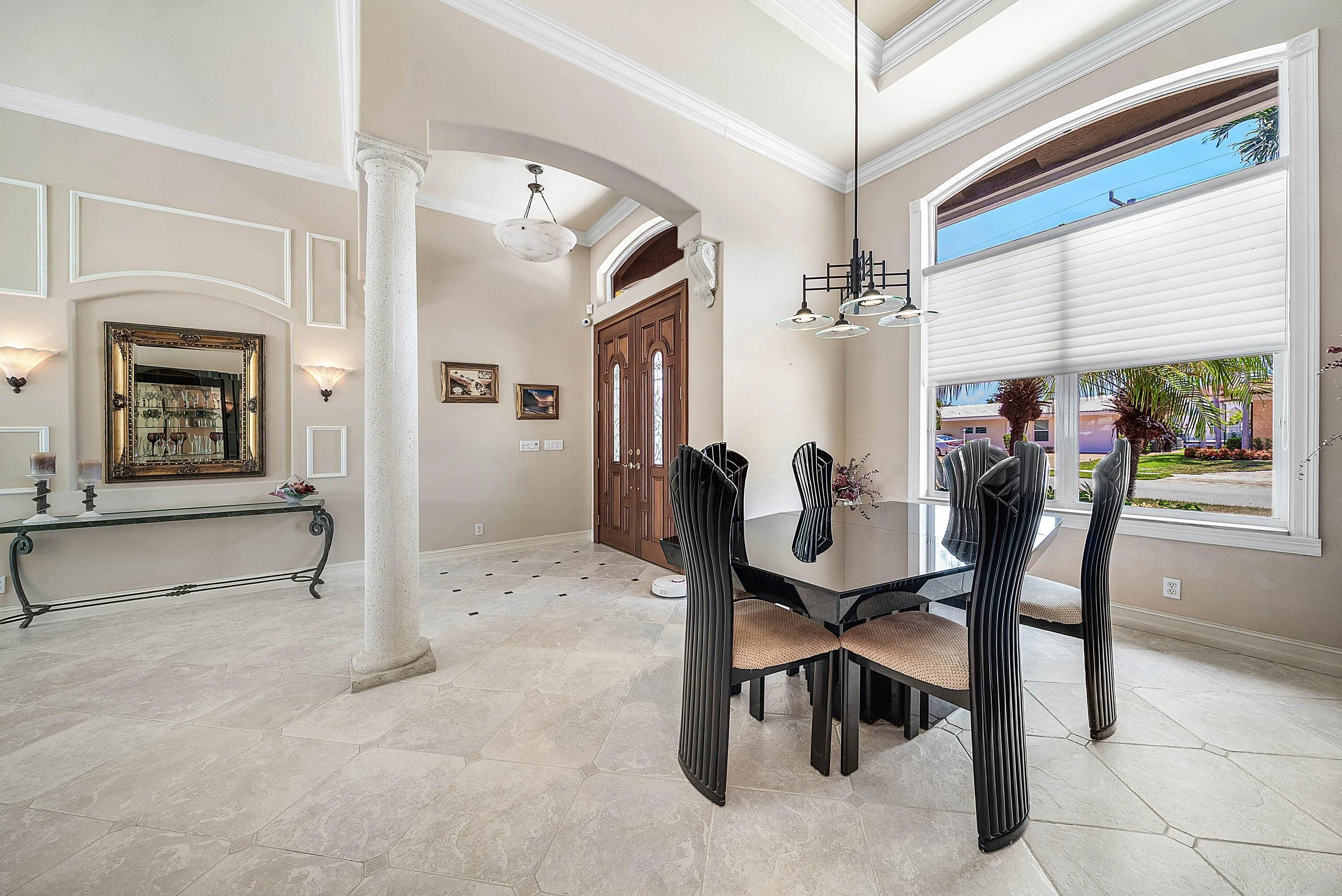 Vaulted ceiling foyer featuring a custom double wood-paneled door, decorative wall paneling, and an arched entryway