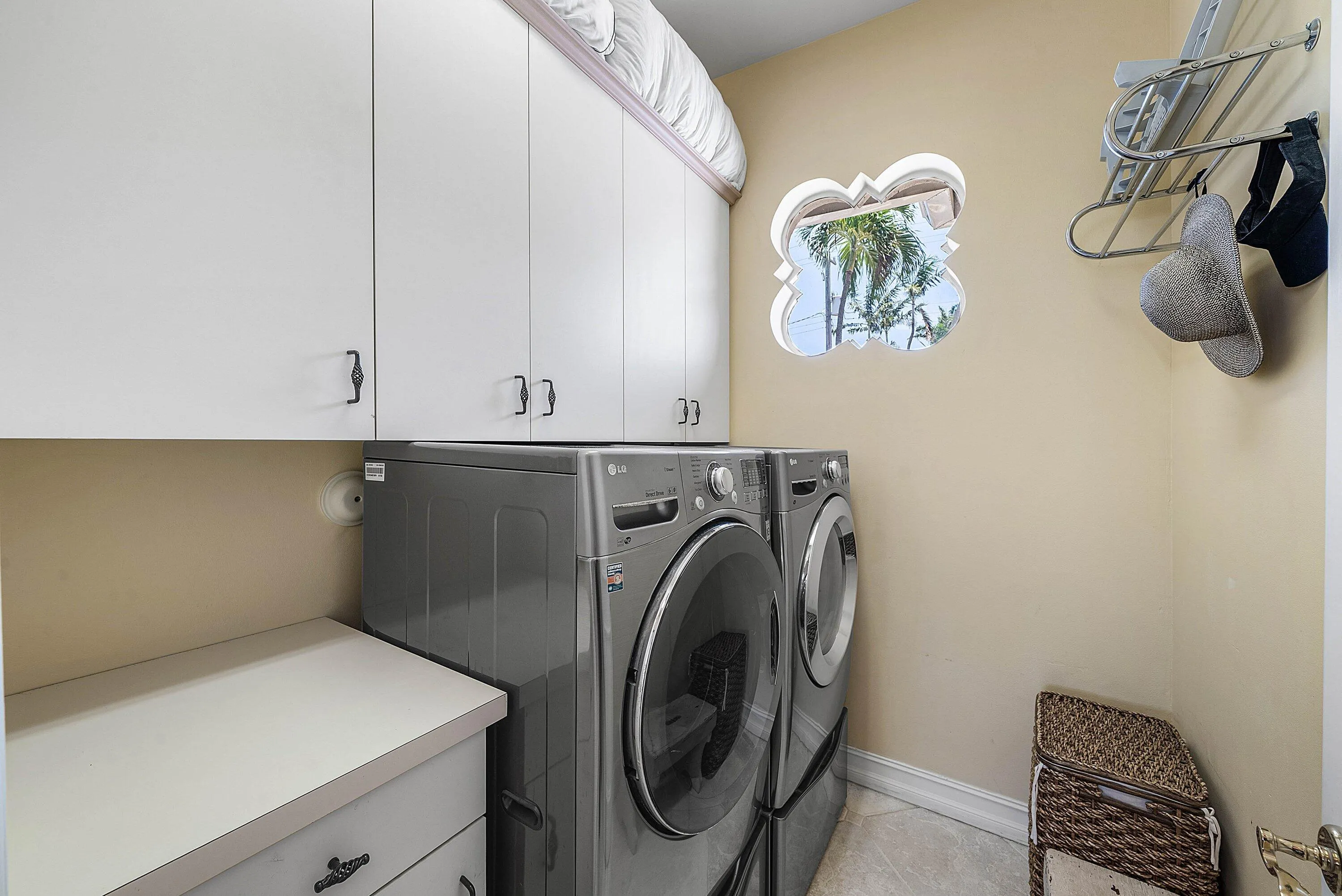 Dedicated laundry room featuring white cabinetry, a decorative window, and light-colored flooring