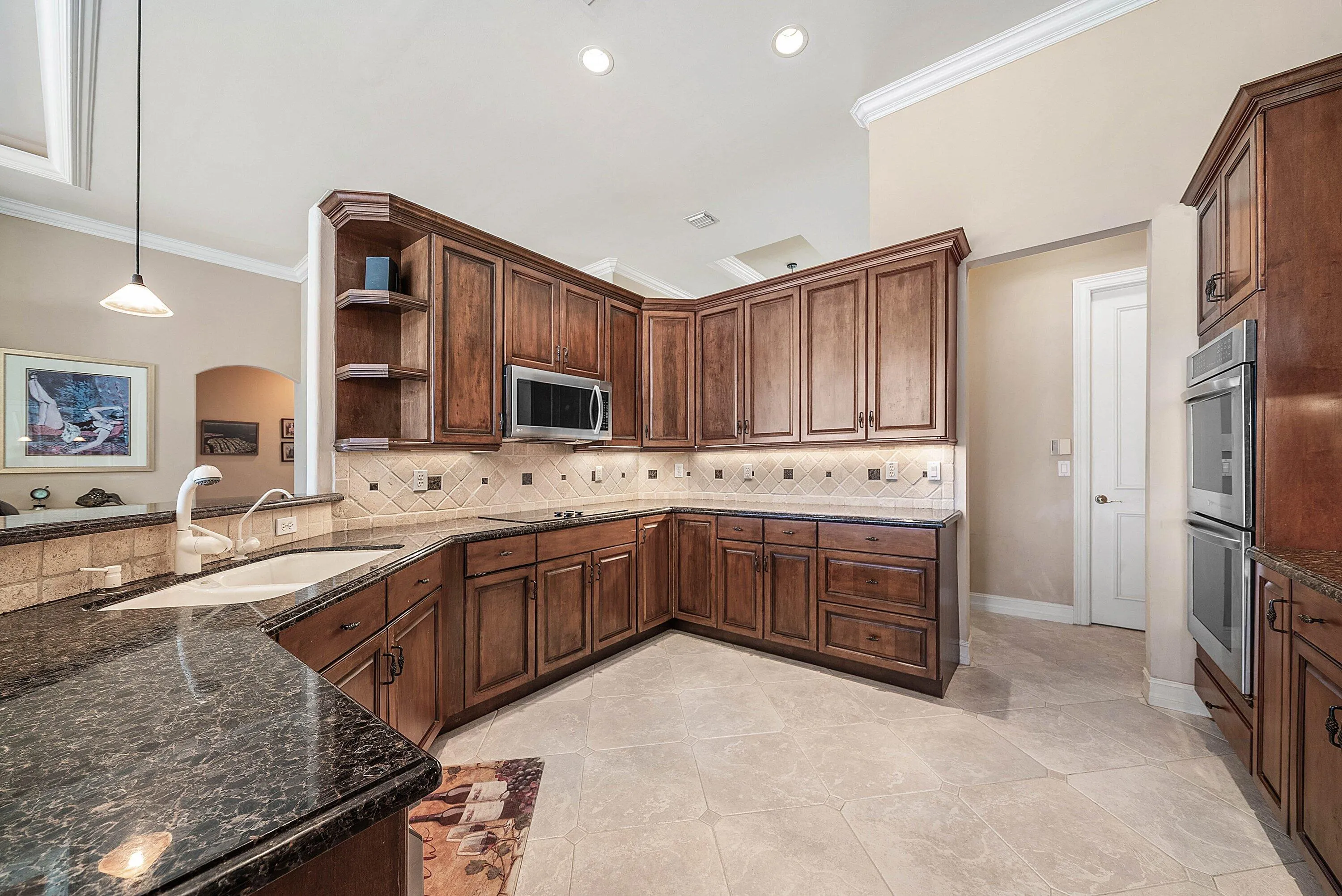 Kitchen featuring rich wood cabinetry, dark speckled countertops, and a tiled backsplash
