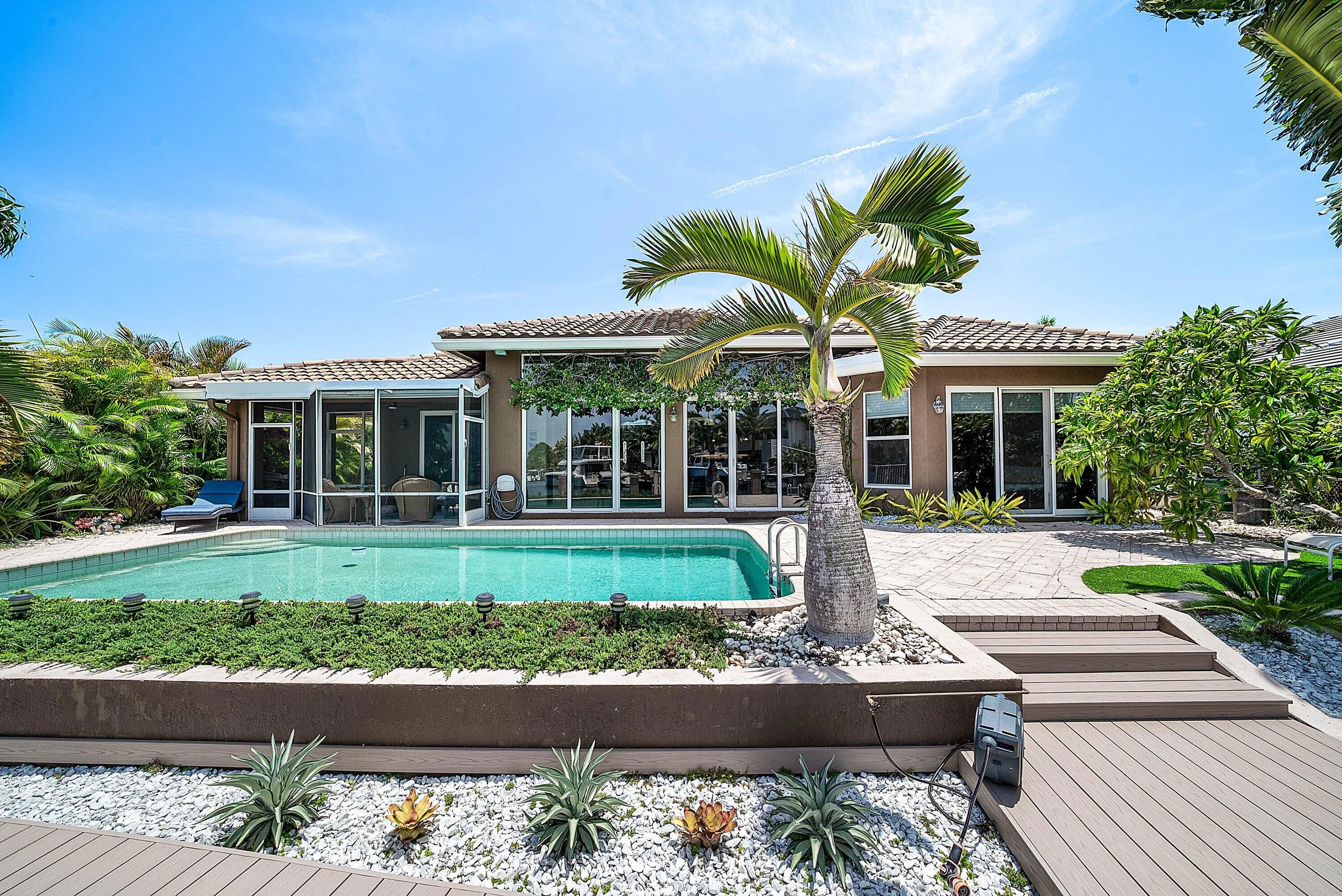 Expansive backyard featuring a rectangular pool, screened patio, and multiple sliding glass doors