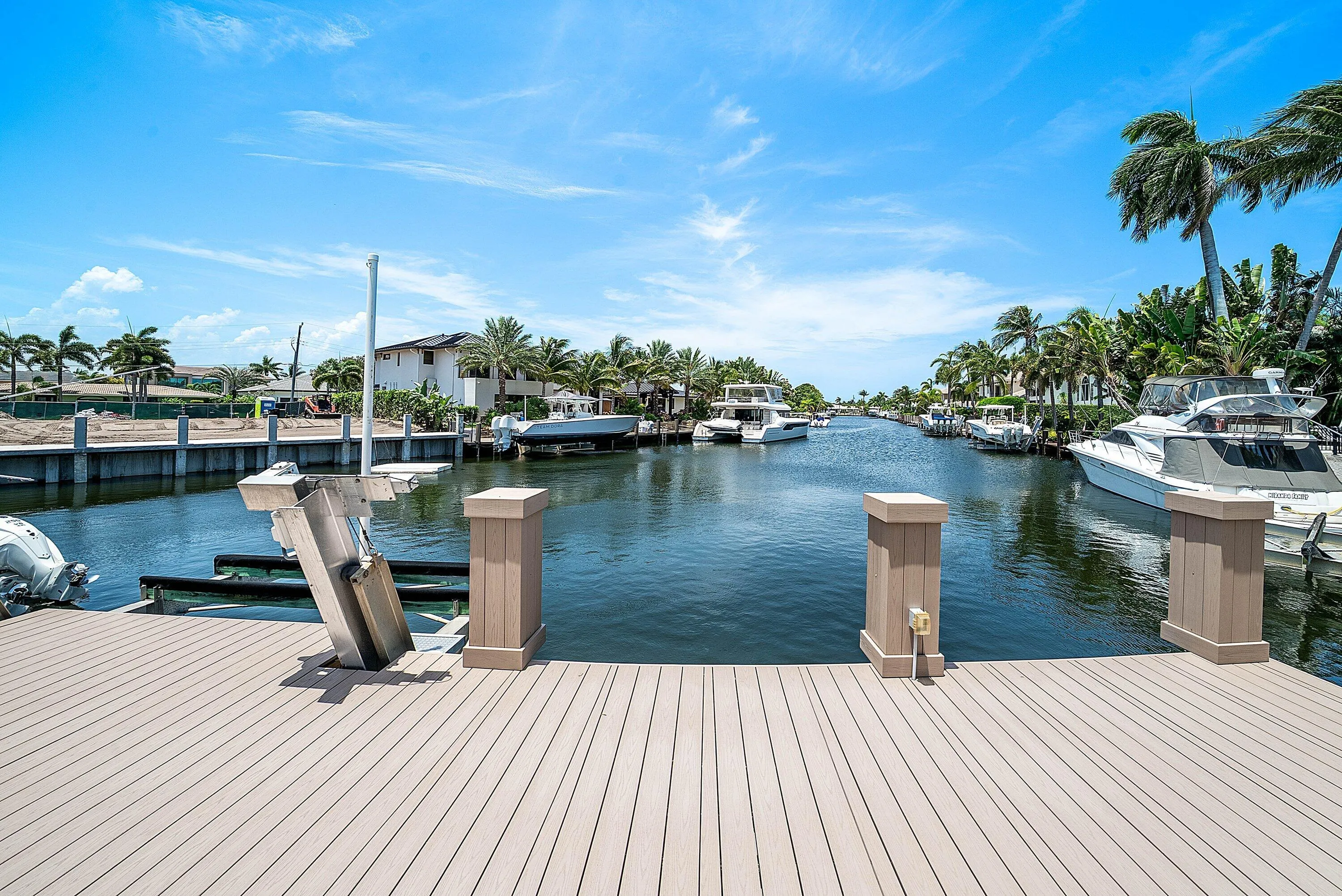 Waterfront property featuring a composite deck, an installed boat lift, and palm trees