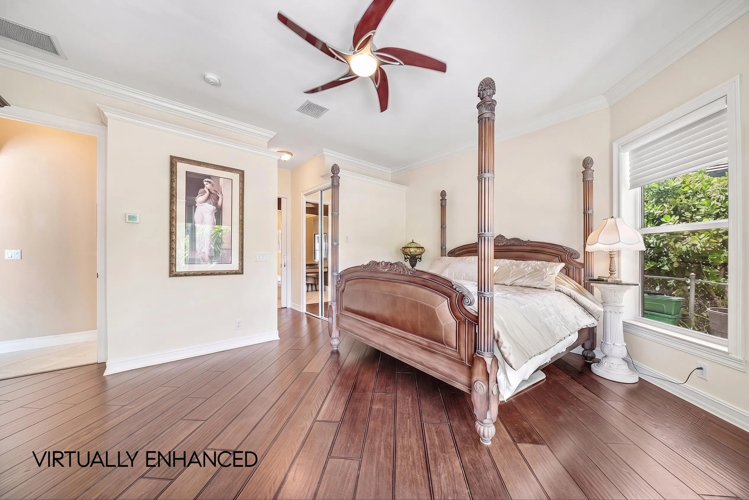 Spacious bedroom featuring rich wood-finish flooring, crown molding, and a ceiling fan with integrated lighting