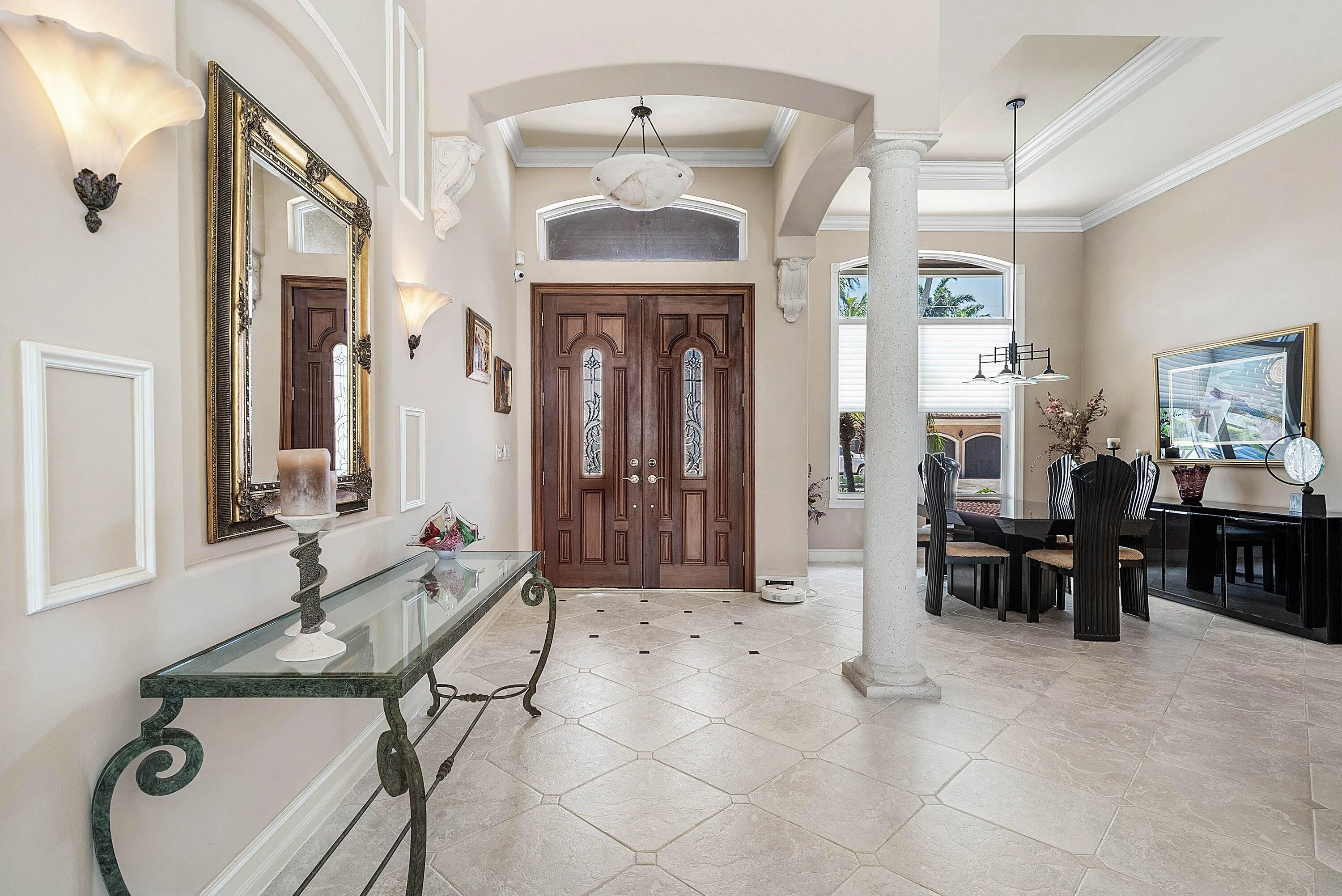 Grand entryway featuring double wood-paneled doors with etched glass, arched doorways, and a decorative column
