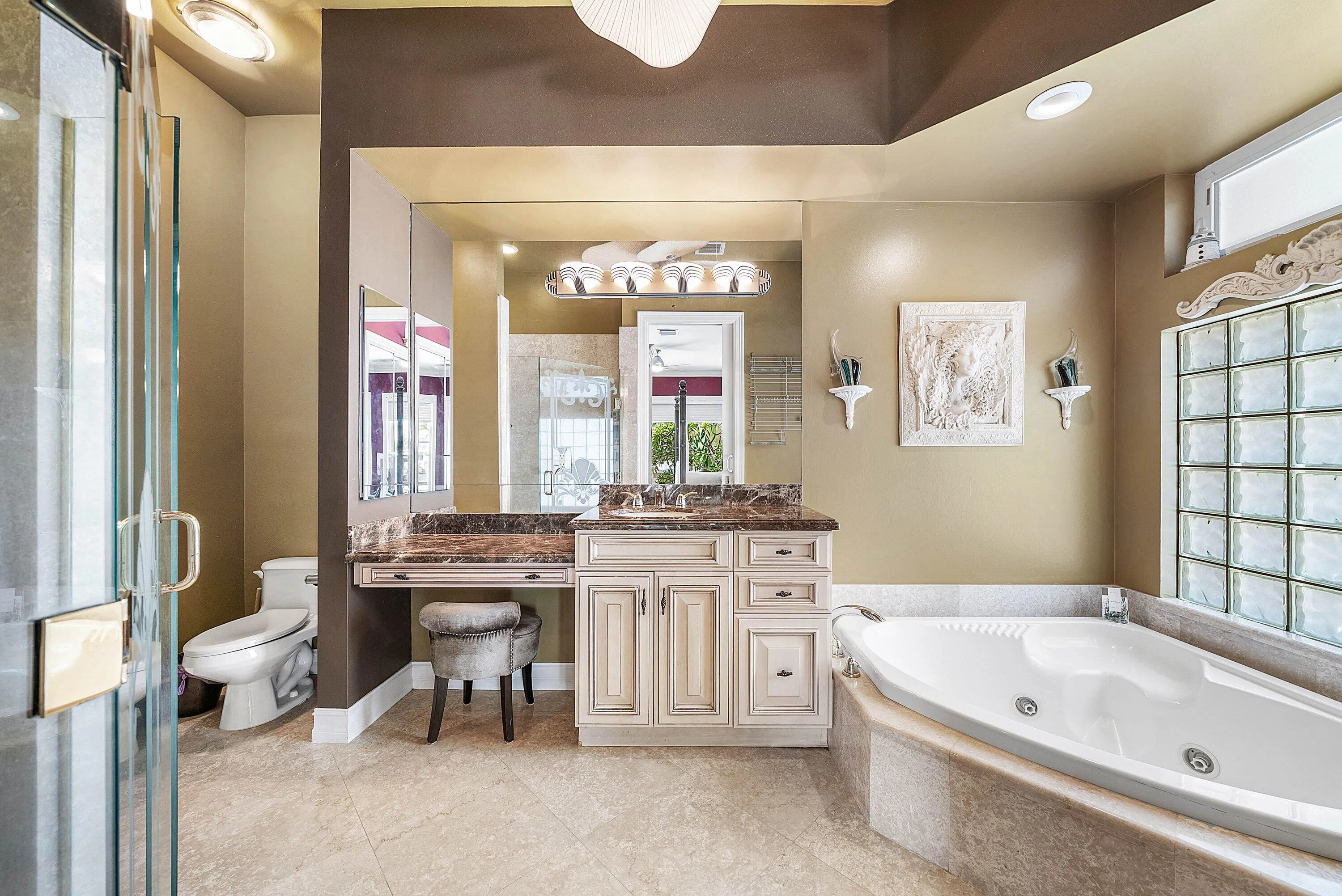 Spacious bathroom featuring a large jetted soaking tub, glass block window, and a separate glass-enclosed shower