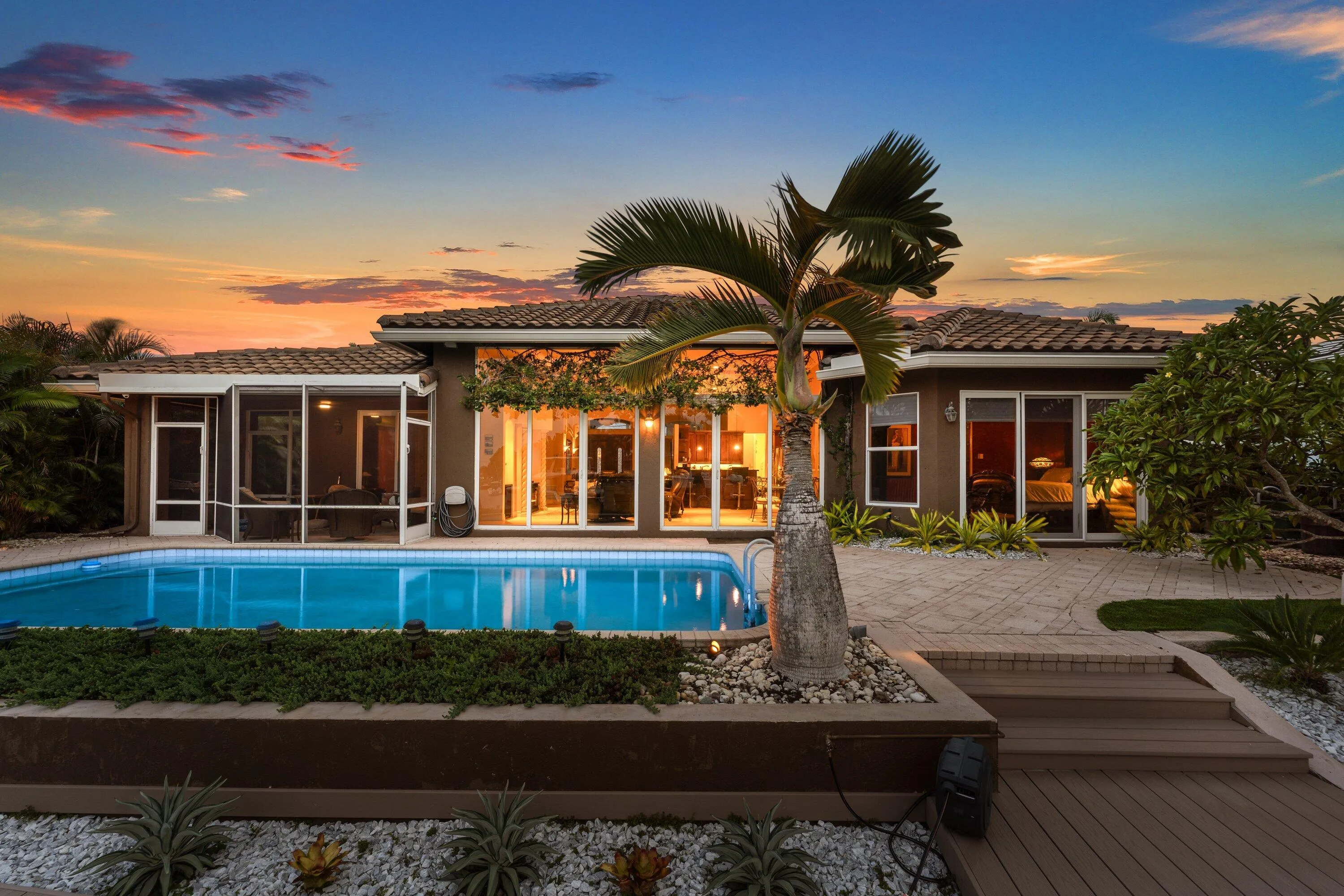 Rear exterior showcasing a rectangular swimming pool, screened-in patio, and a tiled roofline